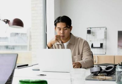 Bright workstation with a person working on a laptop at a white desk.