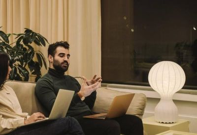 Cozy lounge area with a sofa, globe lamp, and colleagues collaborating on laptops.