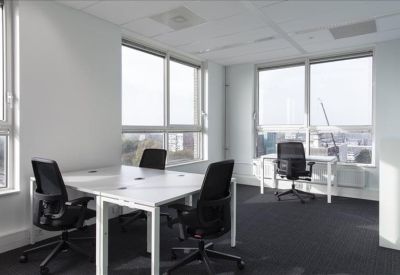Bright corner office with white desks, black chairs, and large windows.
