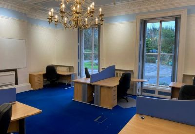 Spacious office with blue carpet and a grand ornate chandelier.