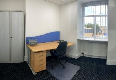 Private office featuring a large wooden desk and tall sash window.