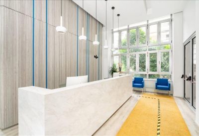 Sleek white reception desk with colorful striped wall panels and blue velvet armchairs.