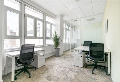 Bright private office with white desks, black mesh chairs, and a potted plant.
