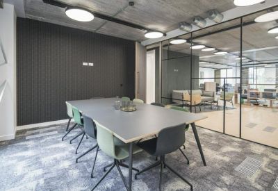 Modern meeting room with a large grey table and colorful chairs.