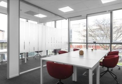 Bright meeting room with a white table, red ergonomic chairs, and large windows.