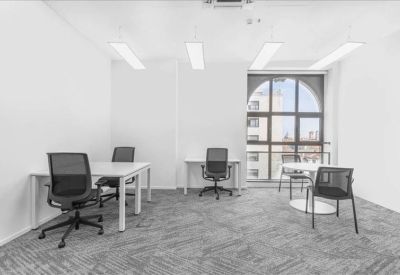 Bright four-person private office with white desks and black mesh chairs.