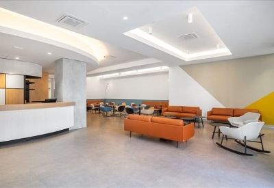 Inviting lobby area with orange sofas and white rocking chairs on a polished floor.