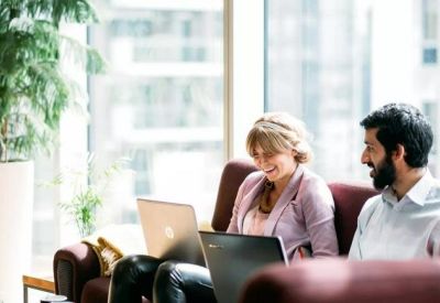 Two people working in a bright office with laptops.