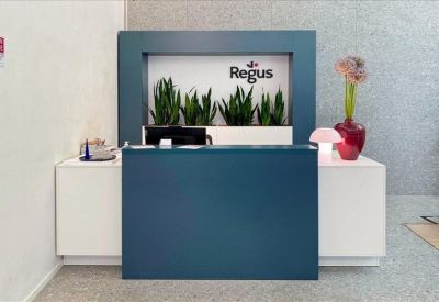 Modern blue reception desk with indoor plants and brand signage.