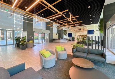 Large open-plan lobby with high ceilings, geometric wooden light fixtures, and grey sofas.