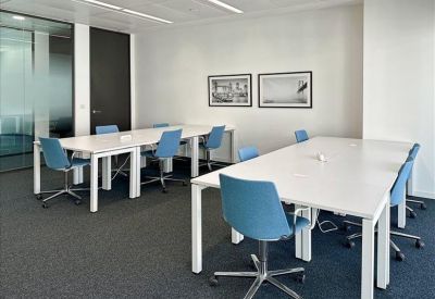 Bright workspace featuring white desks and blue swivel chairs near framed artwork.