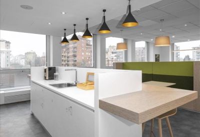Modern office kitchen island with wooden breakfast bar and black pendant lights.