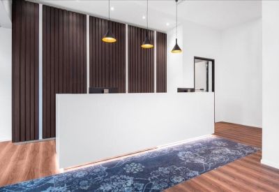 Sleek white reception desk with modern pendant lights and wood-paneled feature wall.