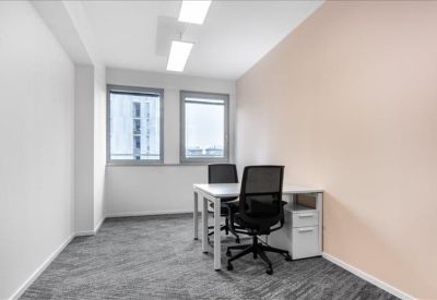 Bright private office with two workstations and white storage units.
