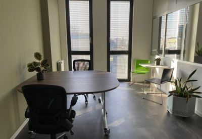 Private office with a table and three chairs by large windows.