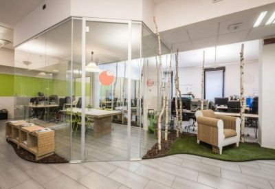 Bright glass-walled meeting room adjacent to a creative indoor garden space with artificial turf.