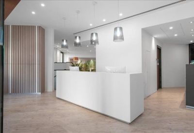 Clean, white reception area with a minimalist front desk and designer glass pendant lights.