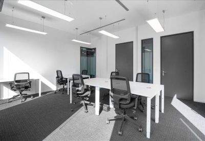 Bright coworking space with white desks and ergonomic black mesh chairs.