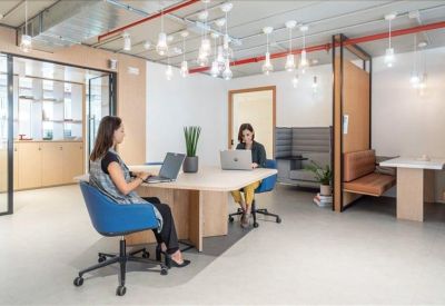 Modern coworking space with people working on laptops under decorative pendant lights.