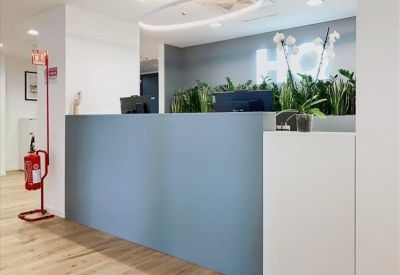 Modern reception desk in shades of blue and white accented by green indoor plants.