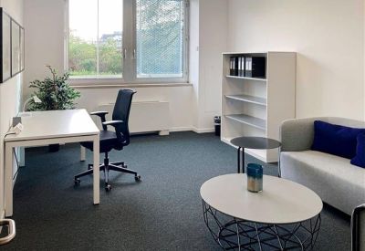 Private office featuring a white desk, blue armchair, and a grey sofa with blue pillows.