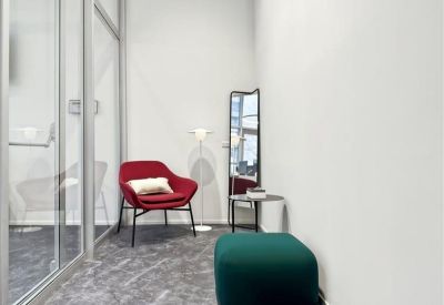 Small waiting area with a red armchair and a green ottoman.