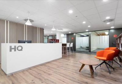 Spacious reception area with a white branded front desk and bright orange armchairs.