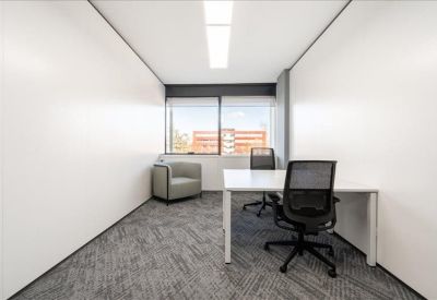 Private office suite featuring a white desk, grey armchair, and large window.