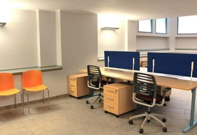 Coworking space with blue dividers and bright orange guest chairs.