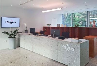 Modern stone-textured reception desk with the Regus logo and monitor stations.