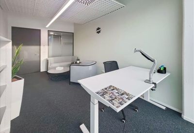 Private office featuring a height-adjustable desk and a small grey meeting table.