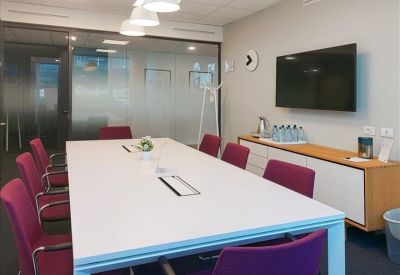 Meeting room with a long white table and purple chairs.