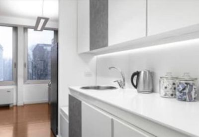 Communal kitchen area with white cabinetry, a sink, and tea making facilities.