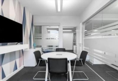 Modern meeting room with a round table and feature wall with geometric patterns.