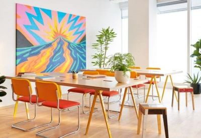Modern meeting space with a large colorful mural and orange chairs.