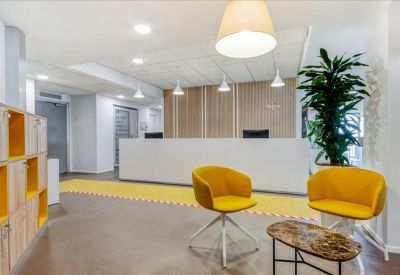 Minimalist reception area with white desk, yellow chairs, and large indoor plant.