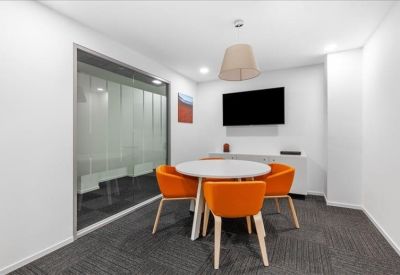Small meeting room featuring a round table and orange upholstered chairs.