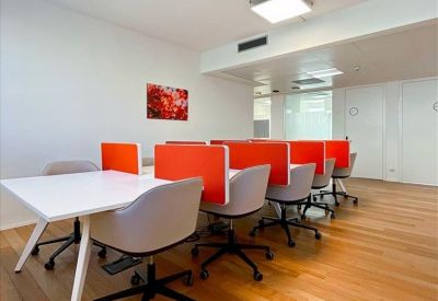 Modern workspace with white tables, grey chairs, and vibrant red privacy screens.