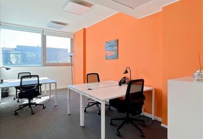 Contemporary office space with orange walls, white desks, and black ergonomic chairs.