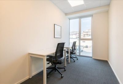 Bright two-person office suite with large floor-to-ceiling windows and gray carpeting.