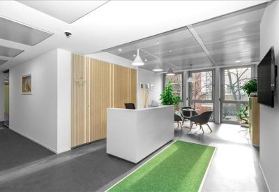 Modern reception desk with a green runner rug and light wood wall panelling.