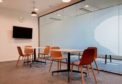 Casual seating area with tables and orange chairs and a wall-mounted TV.