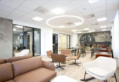 Bright lobby with a mix of leather sofas and modern white rocking chairs under circular light fixtures.