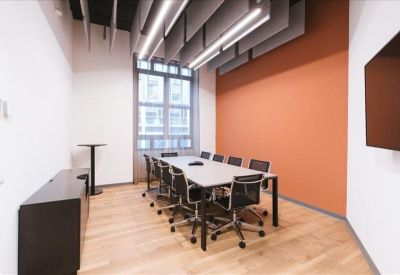 Bright conference room featuring an orange accent wall and sleek grey ceiling baffles.