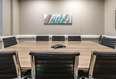 Modern conference room with a large wooden table, black leather chairs, and abstract wall art.