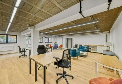 Lounge area with blue armchairs, wooden floors, and bright overhead lighting.