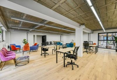 Coworking space featuring colorful velvet seating and multiple individual workstations.