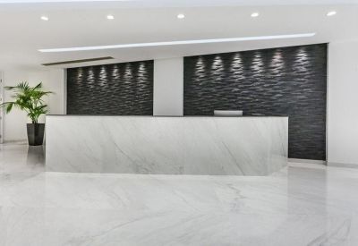 Modern reception lobby with white marble desk and dark textured feature wall panels.