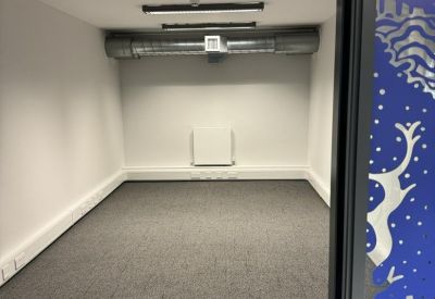 Long, narrow meeting or storage room with white walls and a wall-mounted radiator.