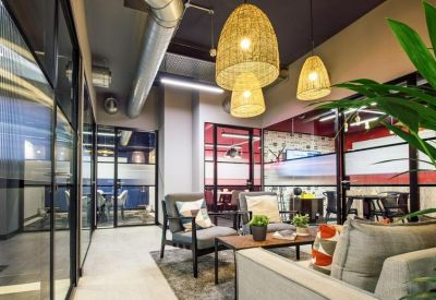 Spacious communal lounge at Waverley House, 7-12 Noel St, Soho with wicker pendant lights and modern armchairs.